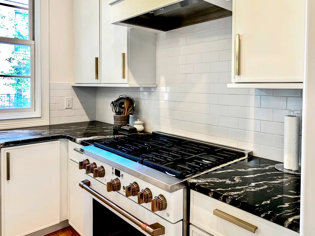 Professional range with black stone countertops and brass details in a Philadelphia kitchen remodel by dRemodeling