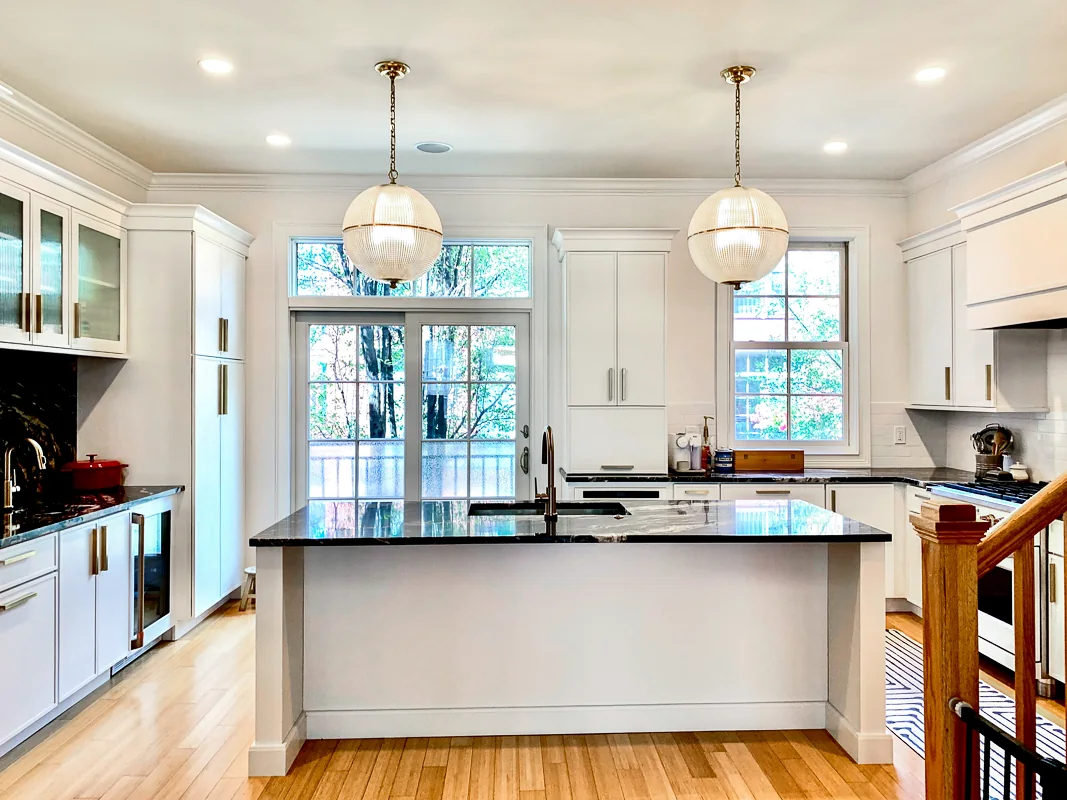 White kitchen remodel with dark stone island and statement lighting in Philadelphia by dRemodeling.